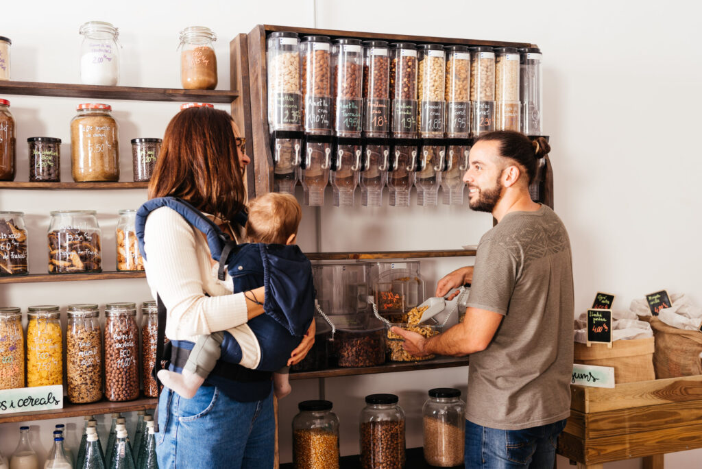 Storekeeper Assists Young Mother Holding a Baby at a Bulk Grocery Store | Účtovníctvo pre každého