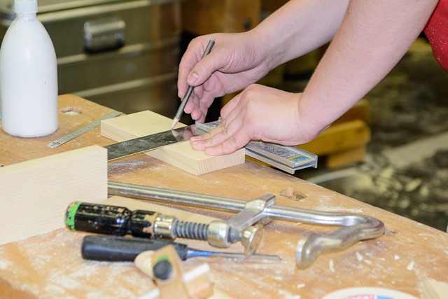 Person shaping a wooden block with a marking knife on a workbench; woodworking tools and chisel nearby